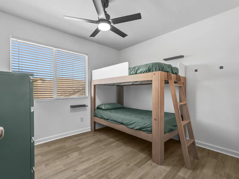 Bedroom with a wooden bunk bed beside a sunny window