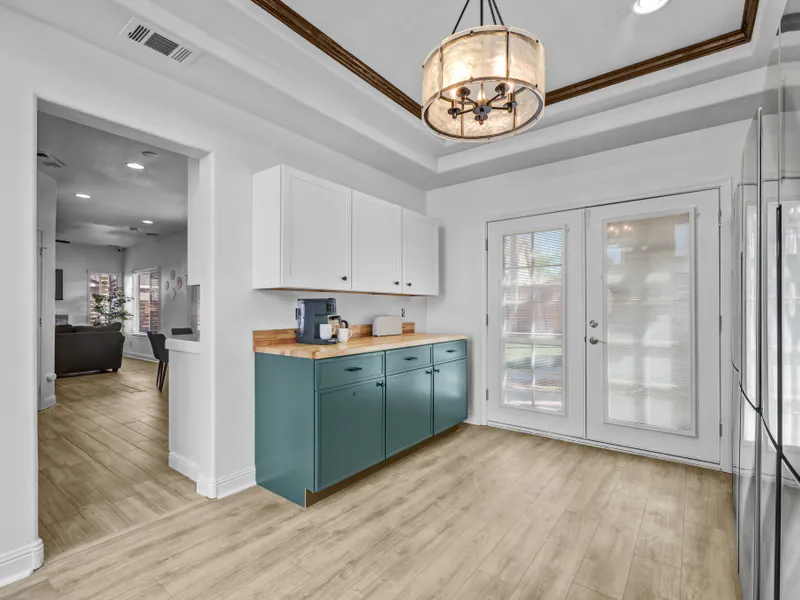 Coffee corner with teal cabinets beside French doors
