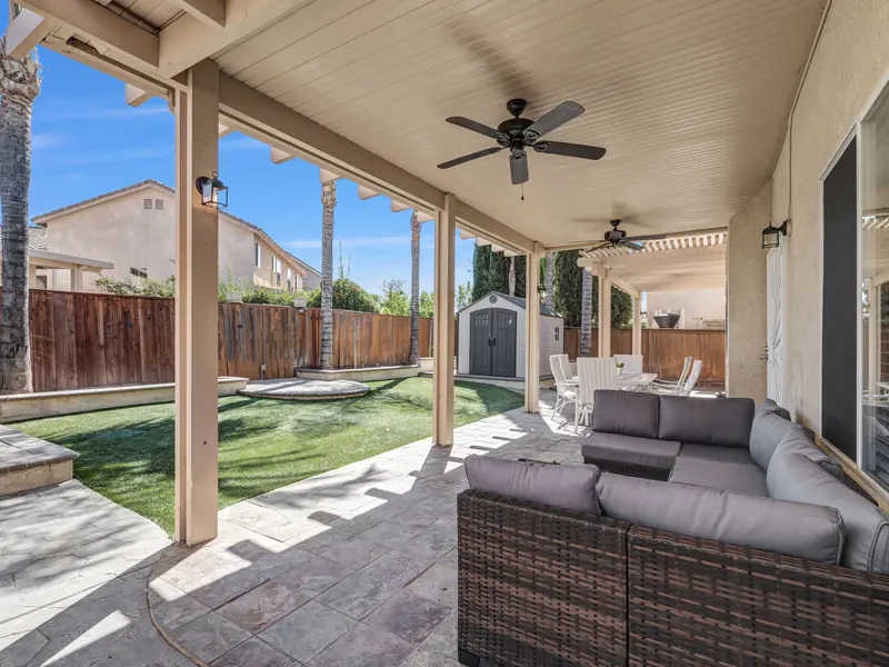 Covered patio with an outdoor sofa and ceiling fans